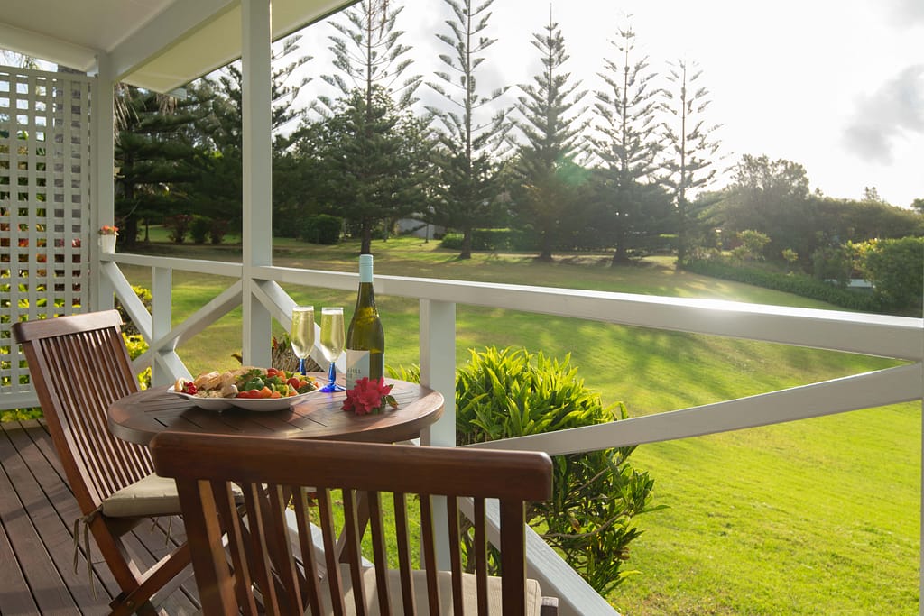 A shot from one of the Poinciana Cottages balcony, softly lit, with tropical garden foliage and a distant valley view.